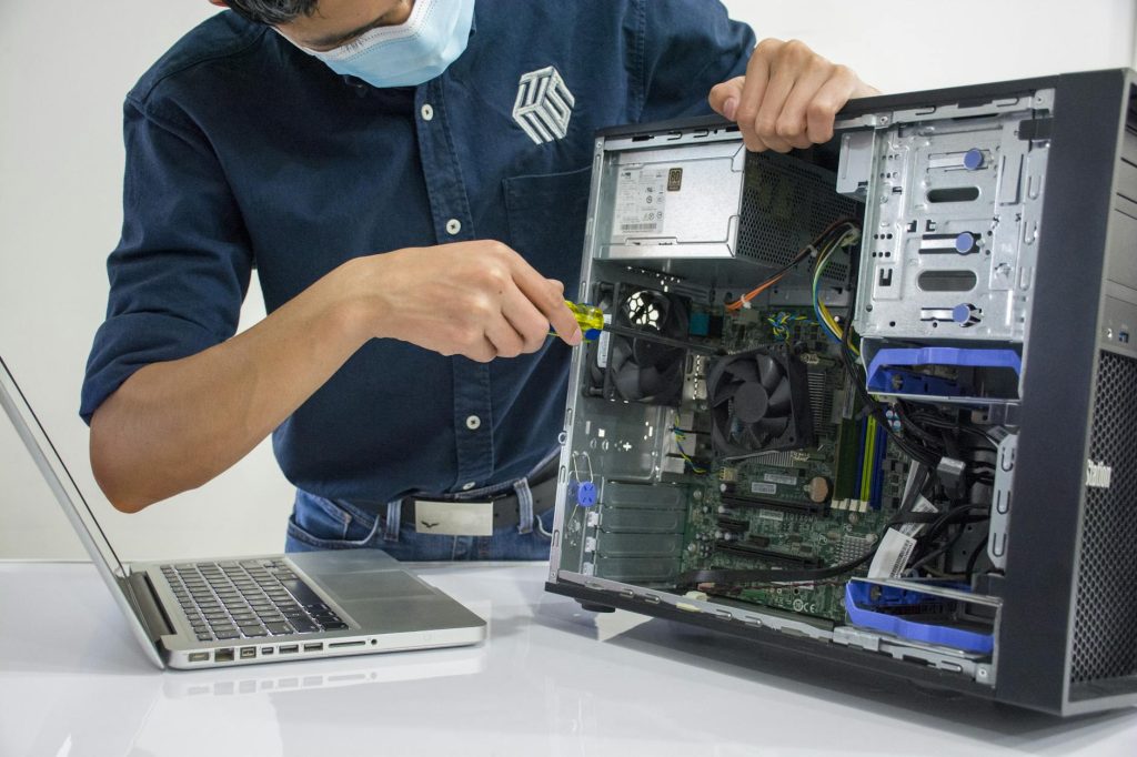 a man wearing a face mask repairing a cpu